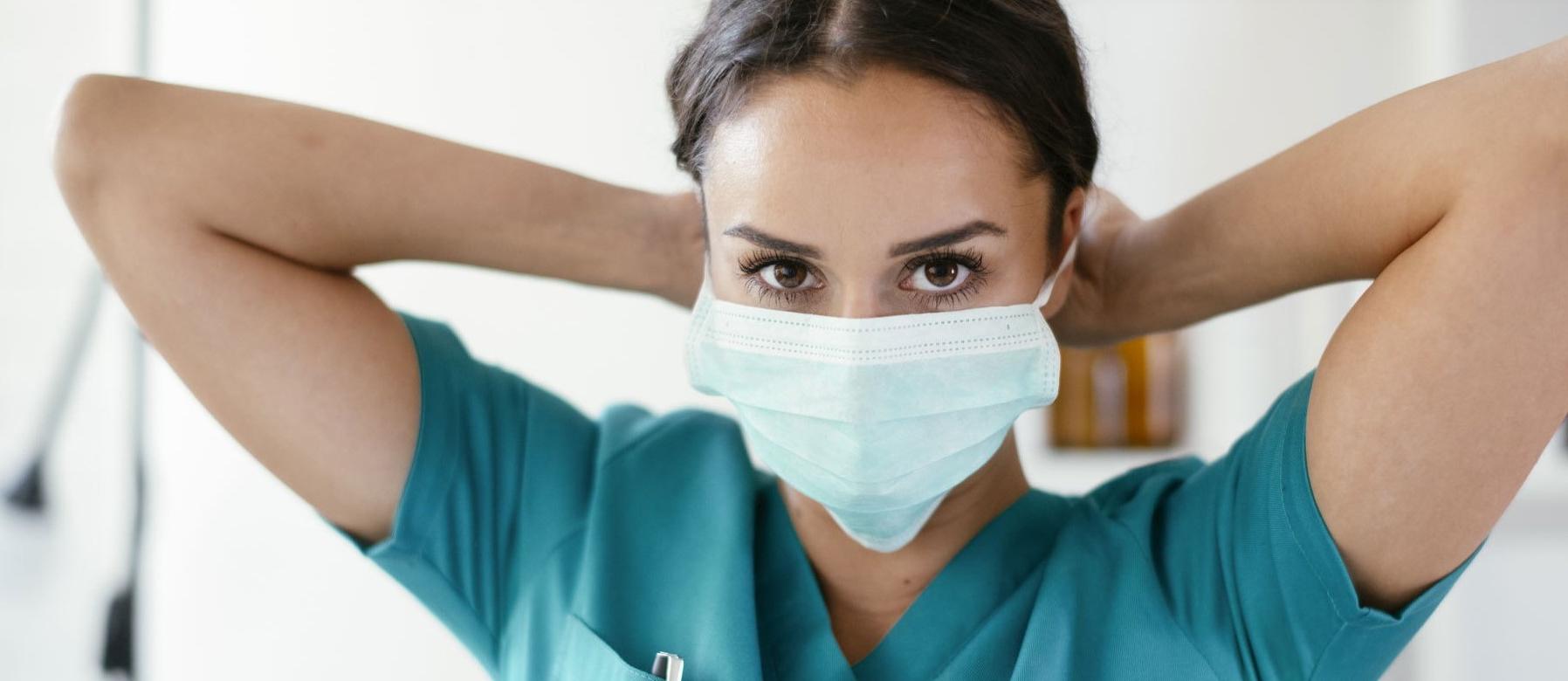 A female licensed practical nurse is wearing scrubs and a mask